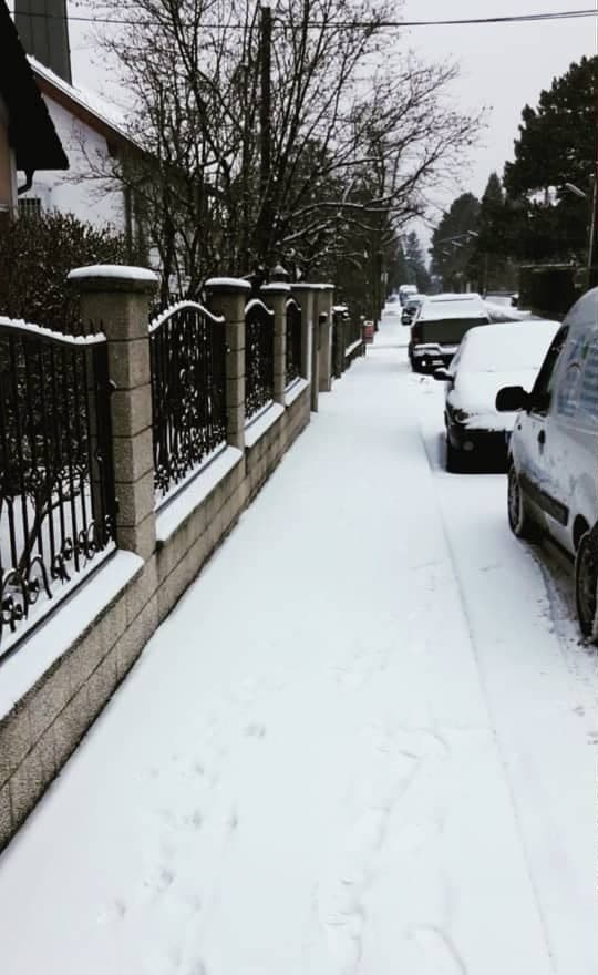 Vorher: Gehweg mit geschlossener Schneedecke und Fußspuren entlang eines Zauns mit Steinpfeilern